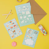 Stationery items including a  birthday card, envelope, stickers, and markers on a yellow background with farm animal themes