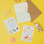 Sticker sheets with dinosaurs, a brown envelope, and stationery items on a yellow background