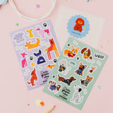 Two sticker sheets with dog illustrations on a pink background with pencils and a party bag.